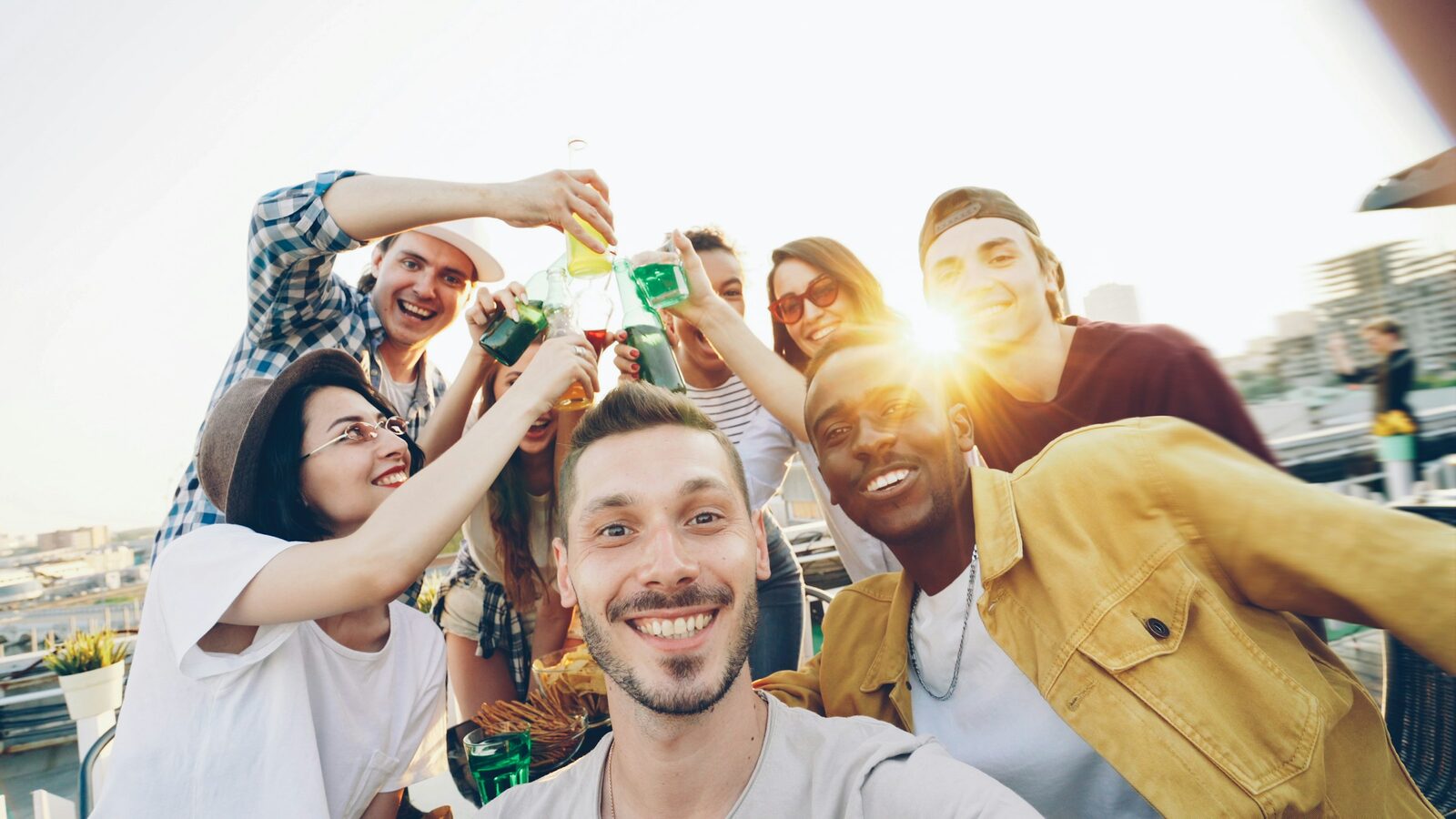 A group of friends raising their drinks in a toast on a sunny rooftop